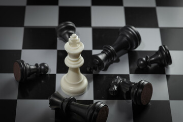 A close-up of a chessboard highlighting the white KING standing out among black pieces, symbolizing...