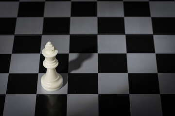 A close-up of a chessboard highlighting the white KING standing out among black pieces, symbolizing strategic thinking, leadership, and decisive planning in overcoming challenges and achieving goals.
