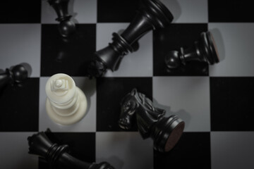 A close-up of a chessboard highlighting the white KING standing out among black pieces, symbolizing...