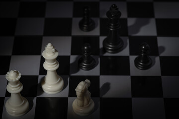 A close-up of a chessboard highlighting the white KING standing out among black pieces, symbolizing...