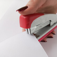 Stapler staples sheets of white paper. Using a stapler to staple documents.
