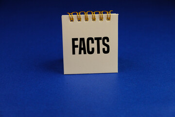 white small notebook with text FACTS. Checking facts and data concept