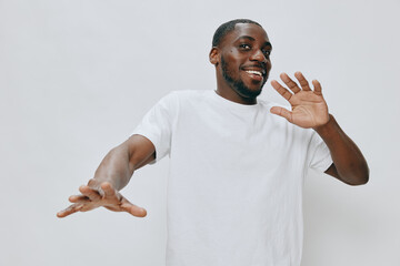 Happy young man in a white t shirt expressing joy and enthusiasm, gesturing warmly against a light...