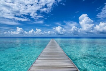 Fototapeta premium Wooden pier extends to turquoise ocean under blue sky.