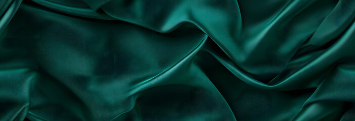 Obraz premium Dark green silk satin background. Beautiful soft folds on the smooth surface of the fabric. Luxury background with copy space for design. Wide banner. Top view. Flat lay.