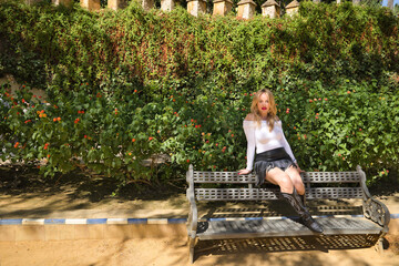A young, beautiful, blonde woman in a white T-shirt, fringed skirt and cowboy boots, looking at the...