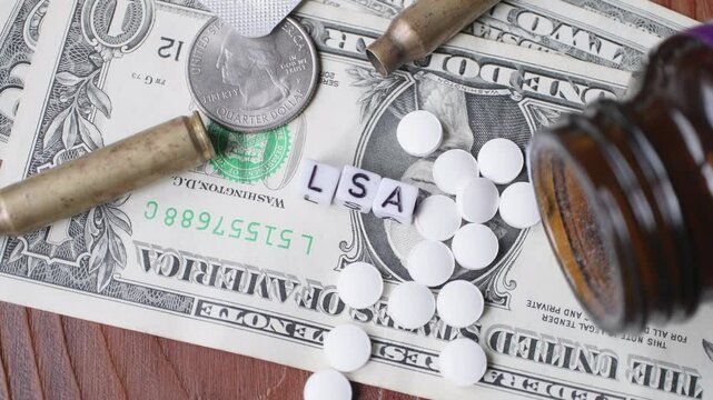 dollars in close-up bullet casings coins and writing cubes with ''LSA''  in slow motion