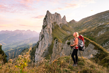 Young woman with backpack hiking in Appenzell Innerrhoden canton of Swiss Alps, Switzerland. Rocky...