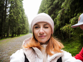 Woman taking a selfie on a hiking trail in the mountains. Woman hiker exploring nature in a misty...