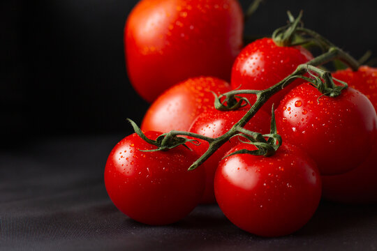 A branch of juicy fresh large tomatoes on a black background