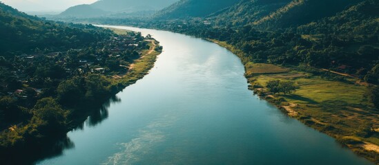 Obraz premium Scenic aerial view of a winding river surrounded by lush green hills and serene landscapes in a tranquil natural setting.