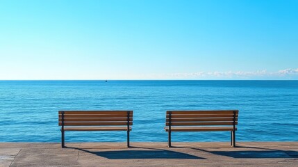 Serene wooden benches beside a tranquil blue sea under a clear sky creating a peaceful atmosphere for relaxation and contemplation.