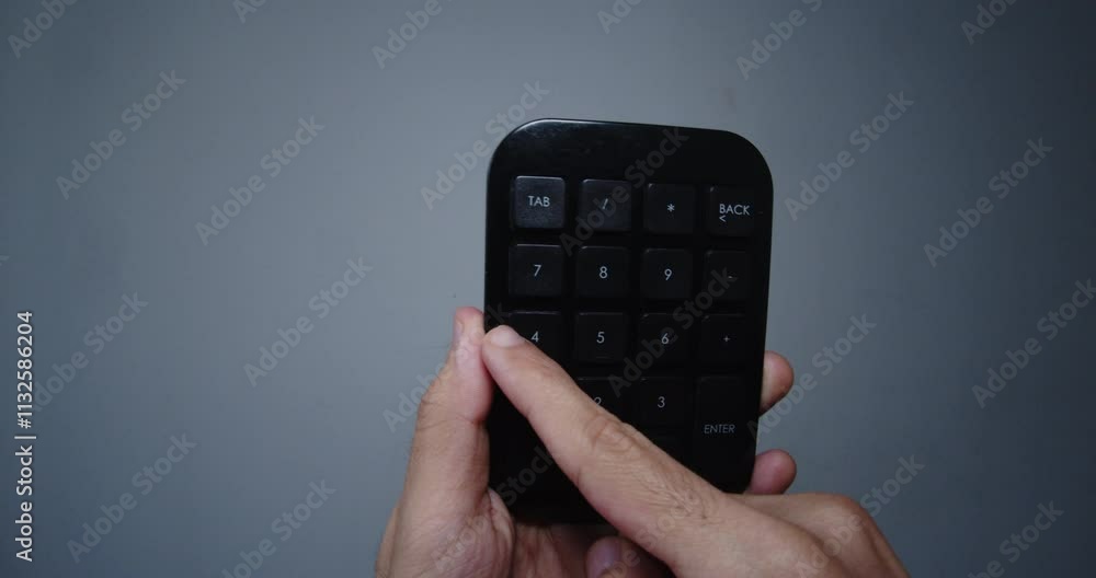 Poster beautiful slow motion close-up shot of a young man's hand holding a small black calculator or mini c