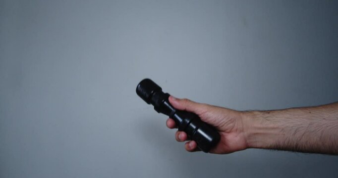 Beautiful frontal hand shot of a young artist musician playing percussion with a black Shaker in action in a room with white walls.