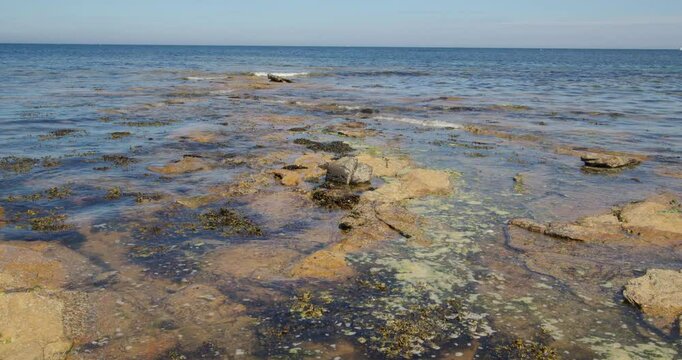 Wide shot of the sea lapping over sedimentary rocks with the tide coming in at Longhoughton beach of the howdiemony sands. Alnwick.