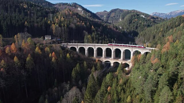 Aerial view of passenger train rides on historical Semmering mountain railway (Semmeringbahn) and famous Kalte Rinne Viaduct, Lower Austria.
