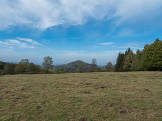 Meadow with autumn colorful forest, trees and hills, blue sky. Landscape in Luzicke hory Lusatian Mountains, Czech Republic.