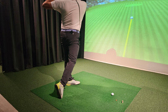 Golfer swings in indoor simulation with projection technology