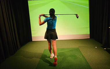 Indoor golf practice session with a player swinging a driver in a simulated environment concept