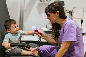Optometrist doing eyesight check to child using colorful flashing toy
