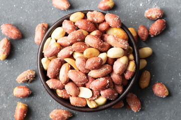 Roasted salty peanut without Shell in bowl or burlap sack on rustic background, concept of nuts