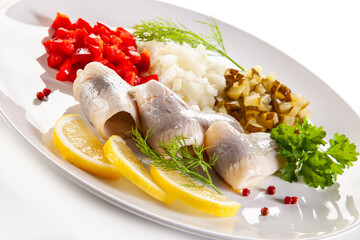 Marinated herring fillets with vegetables on white background