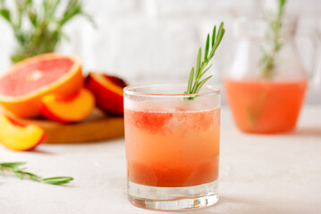 Obraz premium Grapefruit and peach drink, tea, lemonade, cocktail with rosemary. Healthy drink, sugar and alcohol free.