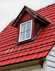 Detail of single old skylight window on an older rural vintage house with red shingles. So called dormer, realistic, with white tones