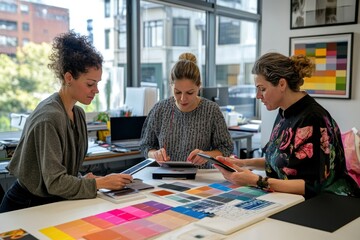 Fototapeta premium Designers Collaborating on Color Palette Selection in Modern Workspace with Color Swatches and Digital Tools for Creative Projects