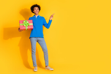 Full body portrait of nice young man giftbox point finger empty space isolated on yellow color background
