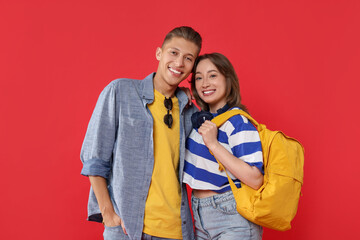 Naklejka premium Traveller with backpack. Happy young woman and man on red background