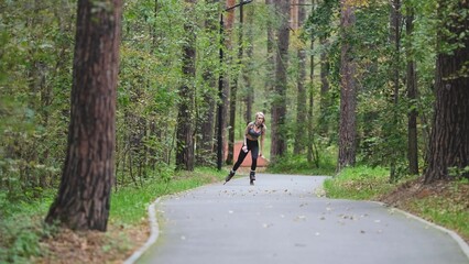 Attractive blonde feels free and light while rollerblading in city park in summer. Stunning...