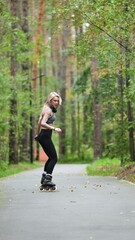 Attractive blonde feels free and light while rollerblading in city park in summer. Stunning...