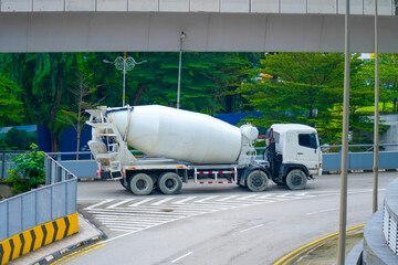 A concrete mixer truck drives steadily down a road under a bridge