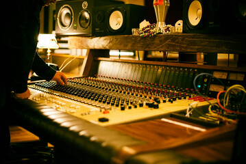 Close-up of a sound engineer adjusting knobs on a vintage audio mixing console in a professional...