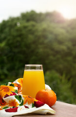 Citrus juice against the background of green trees. A glass of juice on the windowsill.