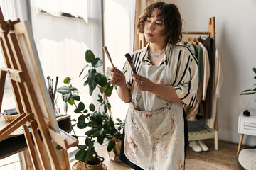 Curly-haired artist passionately creates a beautiful artwork in her stylish apartment. © LIGHTFIELD STUDIOS