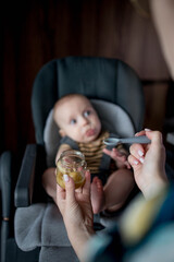 Mother feeding her little baby in kitchen at home. Baby's first food