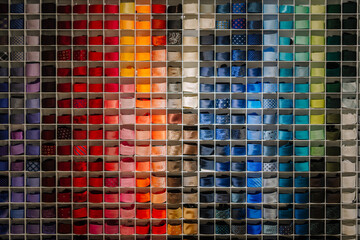 A vibrant and organized wall display of multicolored ties, arranged by hue in individual...