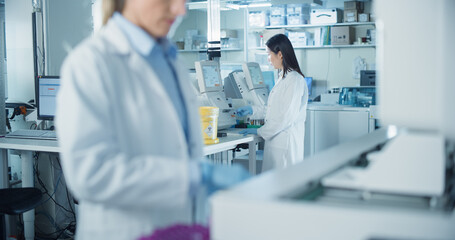Diverse Team Working in a Clinical Laboratory. Focus on an Asian Biomedical Scientist Testing Out...