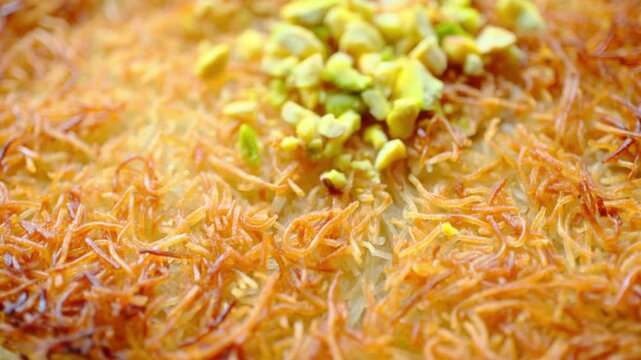 Close-up of local Turkish dessert kunefe with pistachios on a white plate	