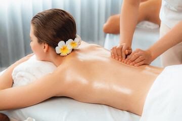 Caucasian couple customer enjoying relaxing anti-stress spa massage and pampering with beauty skin recreation leisure in day light ambient salon spa at luxury resort or hotel. Quiescent