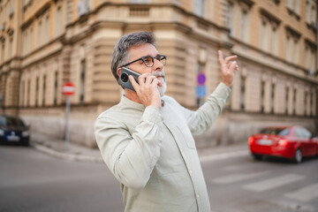 Obraz premium happy senior man stand and talk on mobile phone on the street