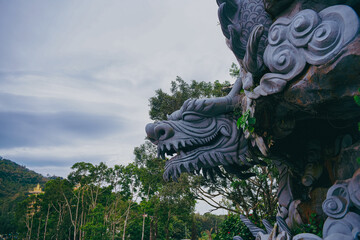 A dragon statue stands next to a temple