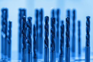 A collection of precision drill bits stands prominently in the workshop, reflecting their sharp...