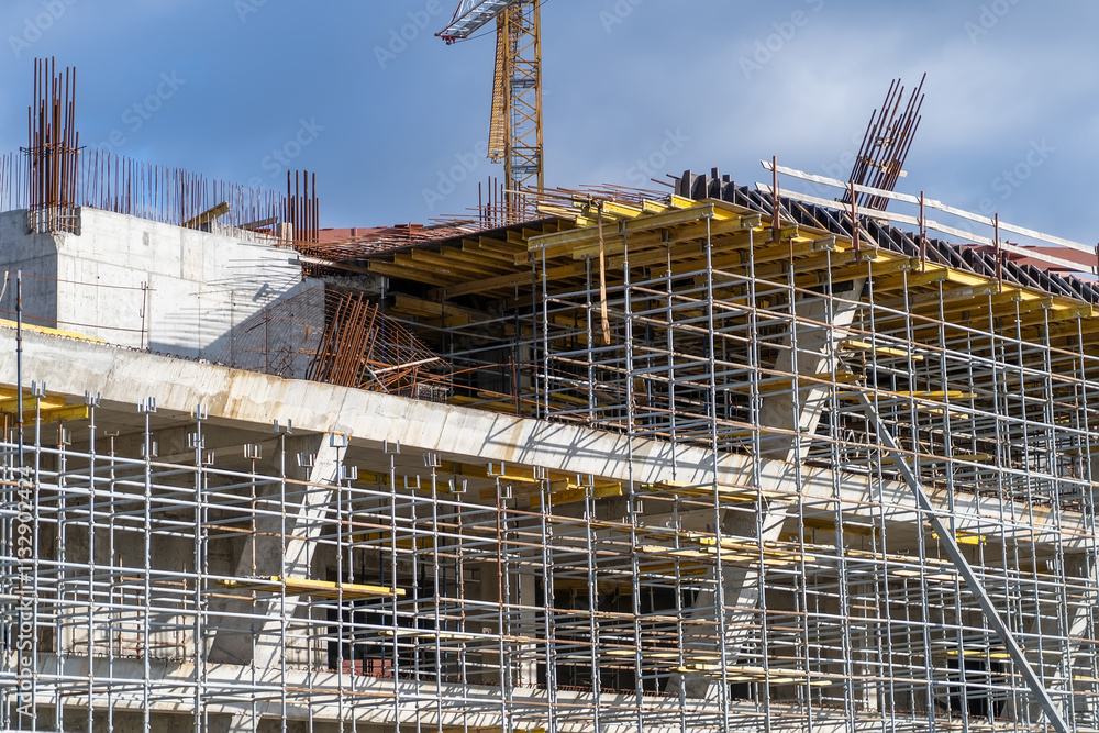 Poster workers are actively constructing a multi-story building with scaffolding and cranes, ensuring safet