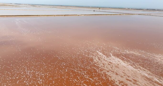 Aerial closeup of the tanks of a large salt mine. The water in the salt pan is red.