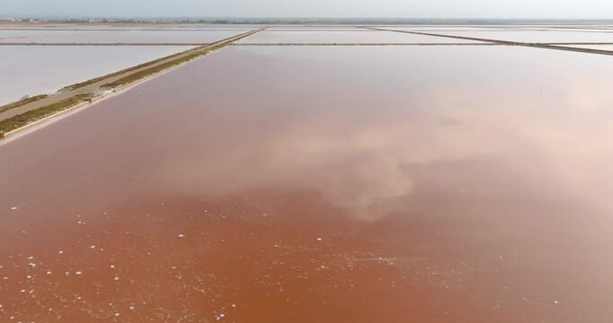 Aerial closeup of the tanks of a large salt mine. The water in the salt pan is red.