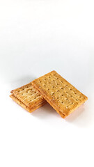 A detailed shot of two golden brown crackers stacked together on a clean white surface, highlighting their texture and simplicity.