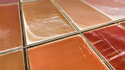 Aerial closeup of the tanks of a large salt mine. The water in the salt pan is red.